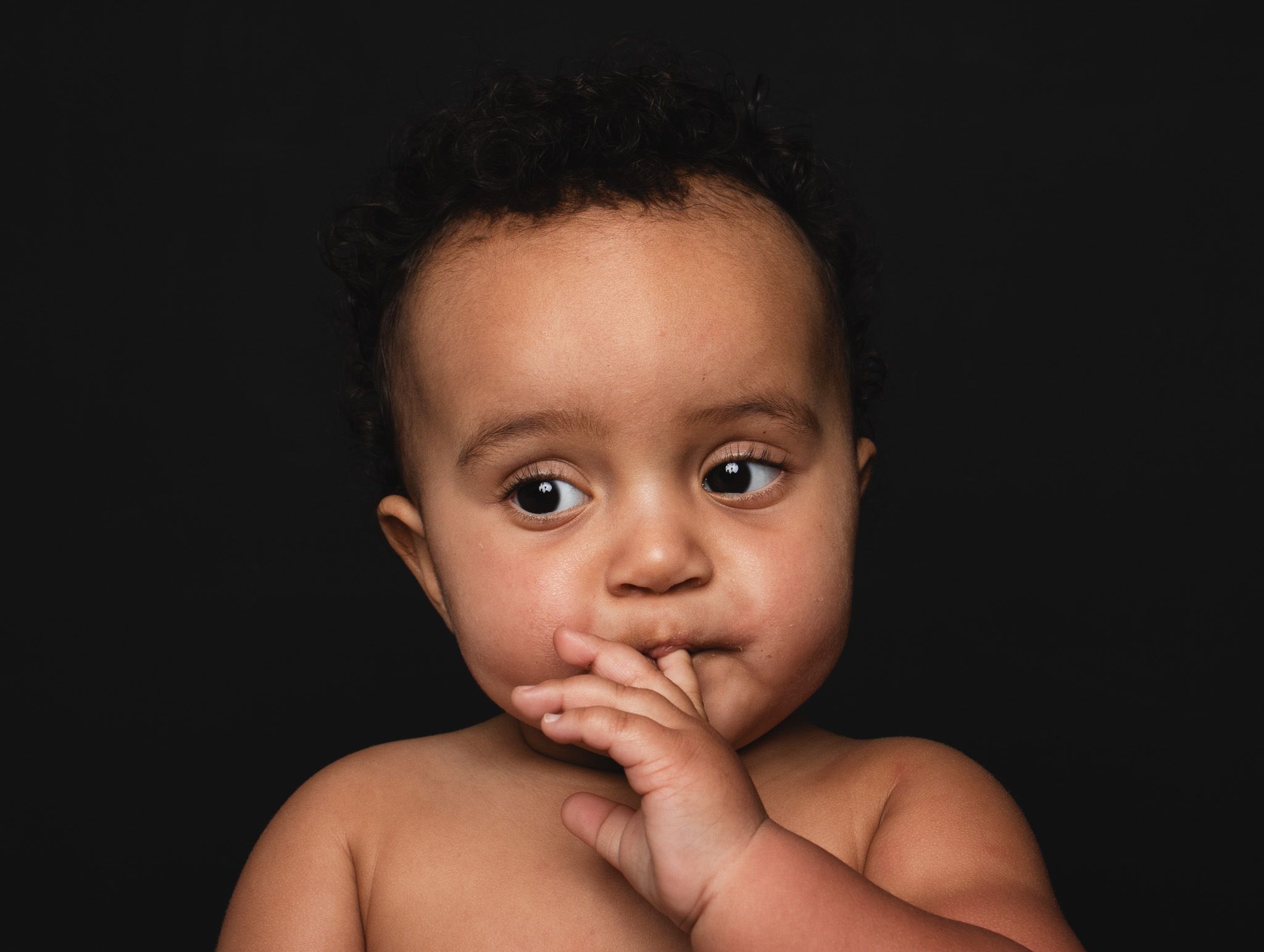 A series of candid black and white portraits showing a child's various expressions against a dark background.