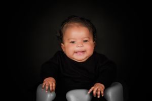 A series of black and white photos showing small hands and feet of an infant against a dark background.