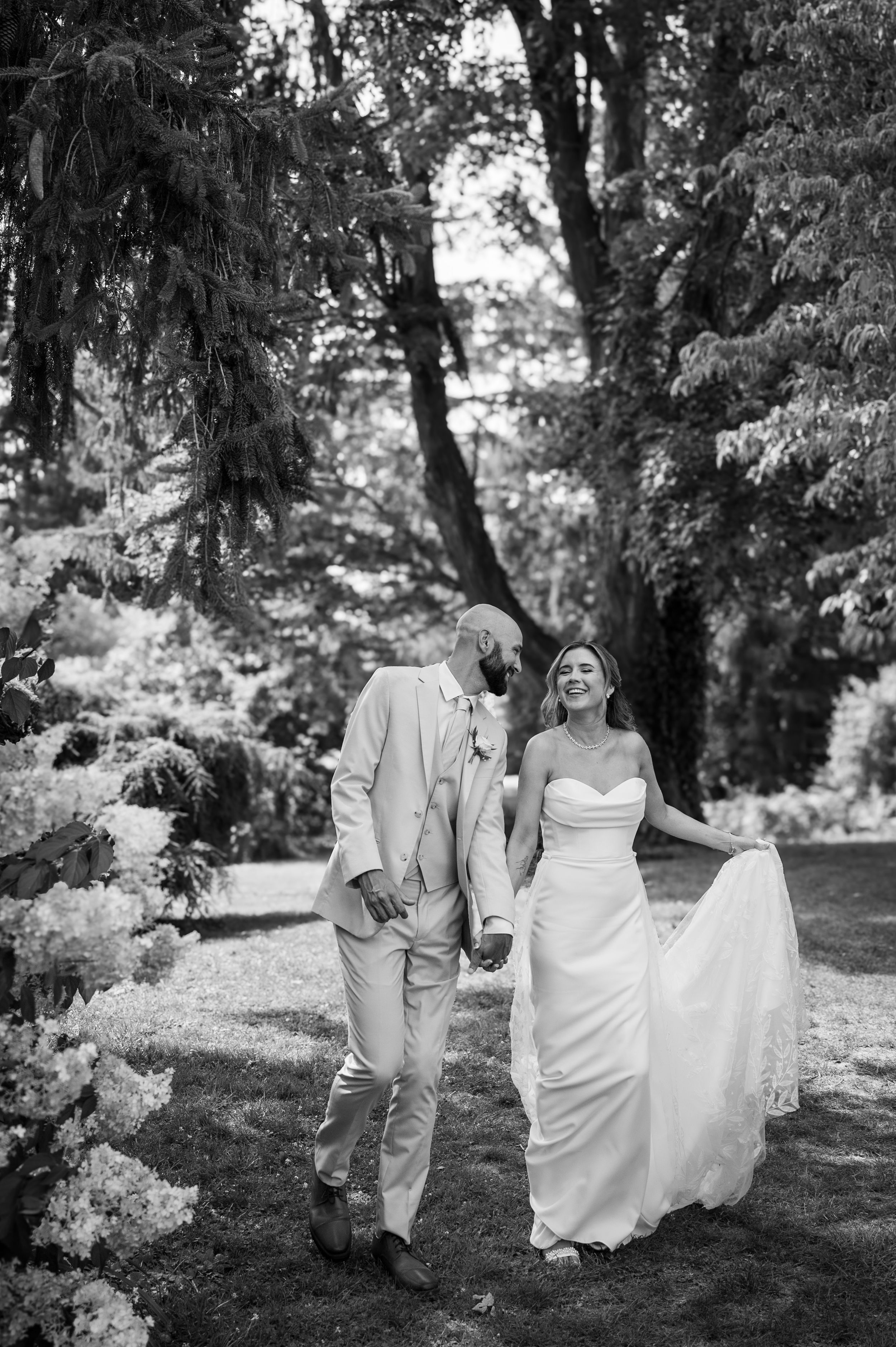 Couple walks together through a lush garden path in wedding attire.