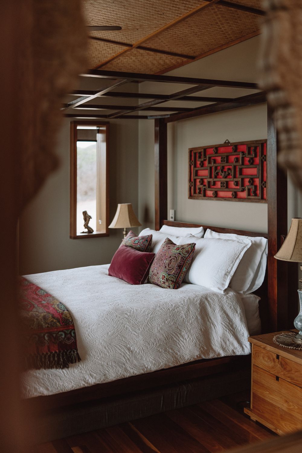 Modern bedroom with white bedding and red geometric wall art.