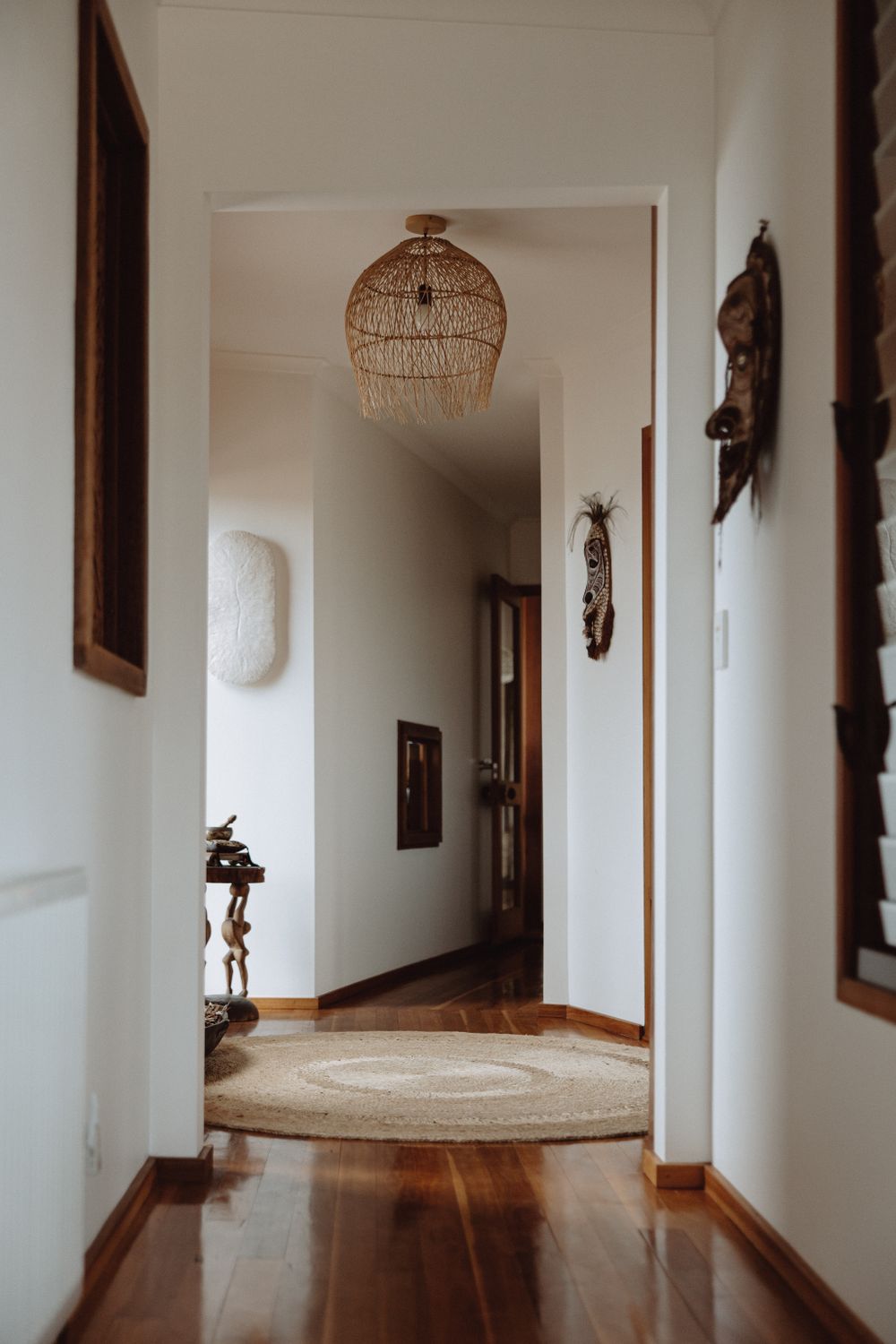 Long white hallway with hardwood flooring and decorative wall art featuring natural lighting.