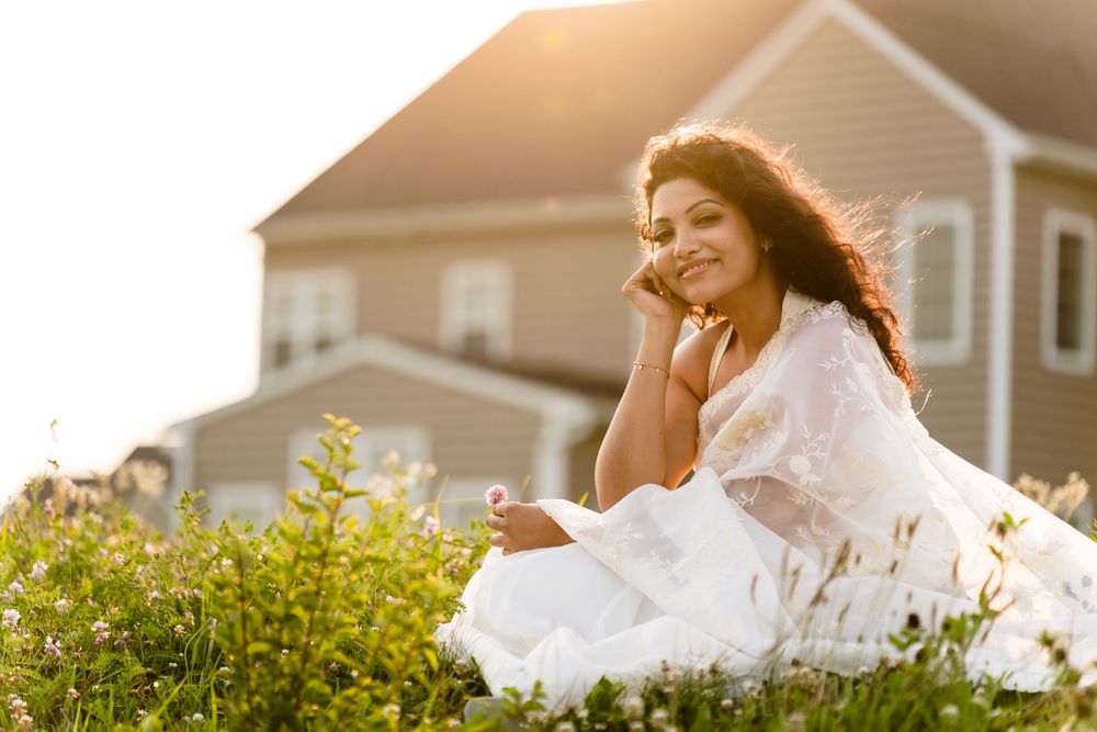 A person in a flowing white dress twirls joyfully in a sunlit meadow at golden hour.