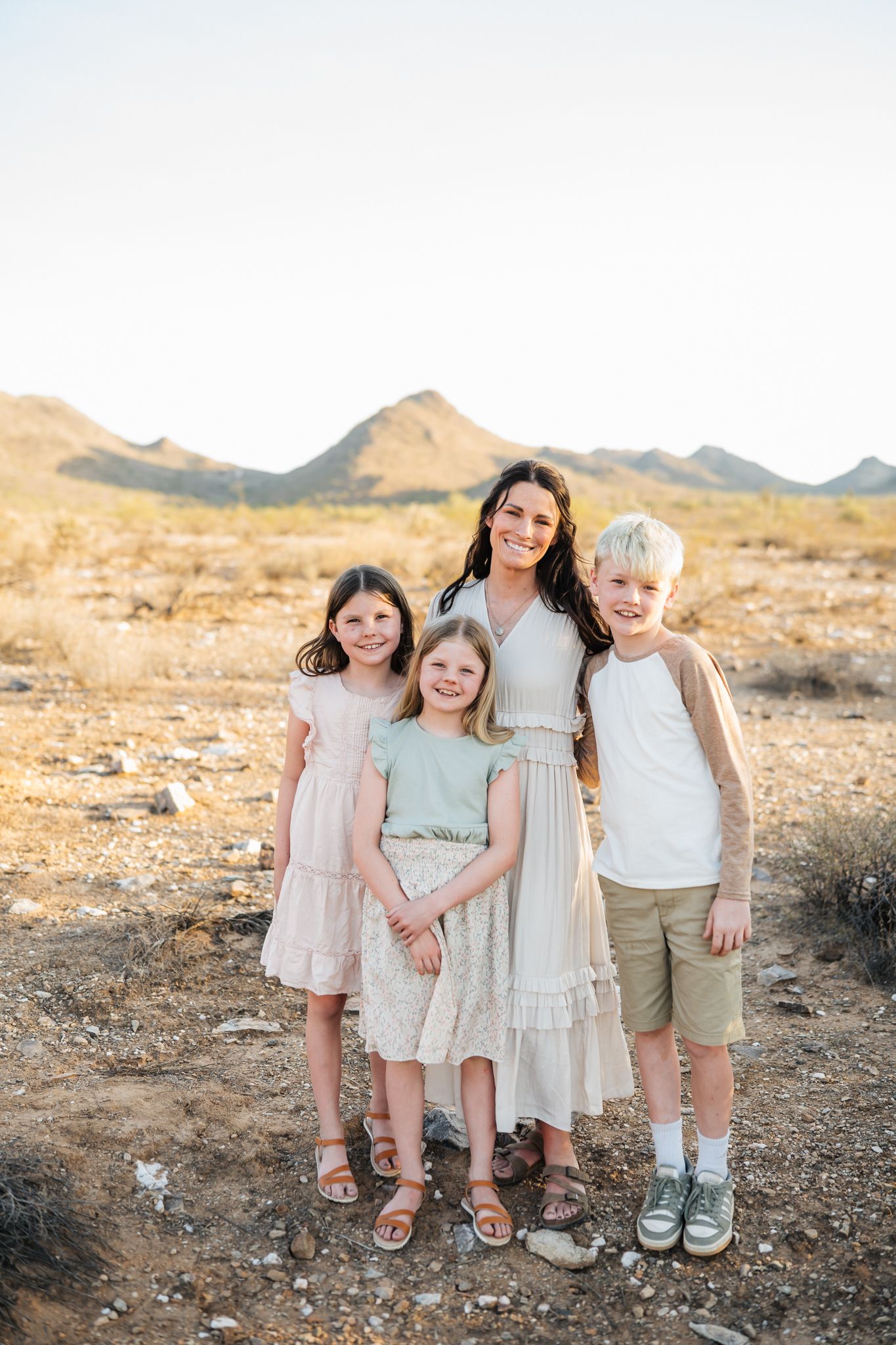Family group poses together in desert landscape with mountains and yellow brush in background.