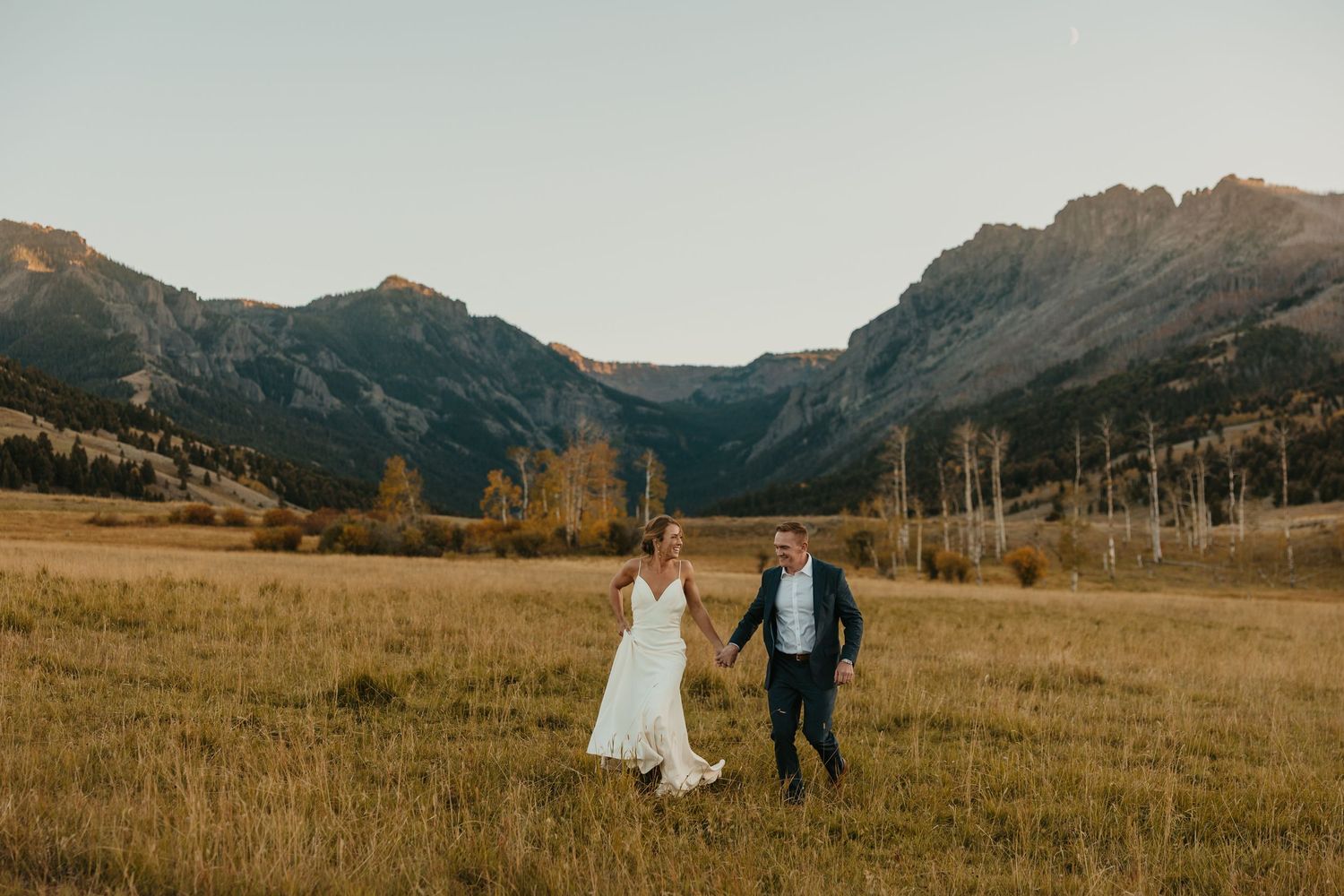 Cowgirl Bride standing with her horse in her wedding dress captured by a Billings Montana Wedding Photographer in a stunning field