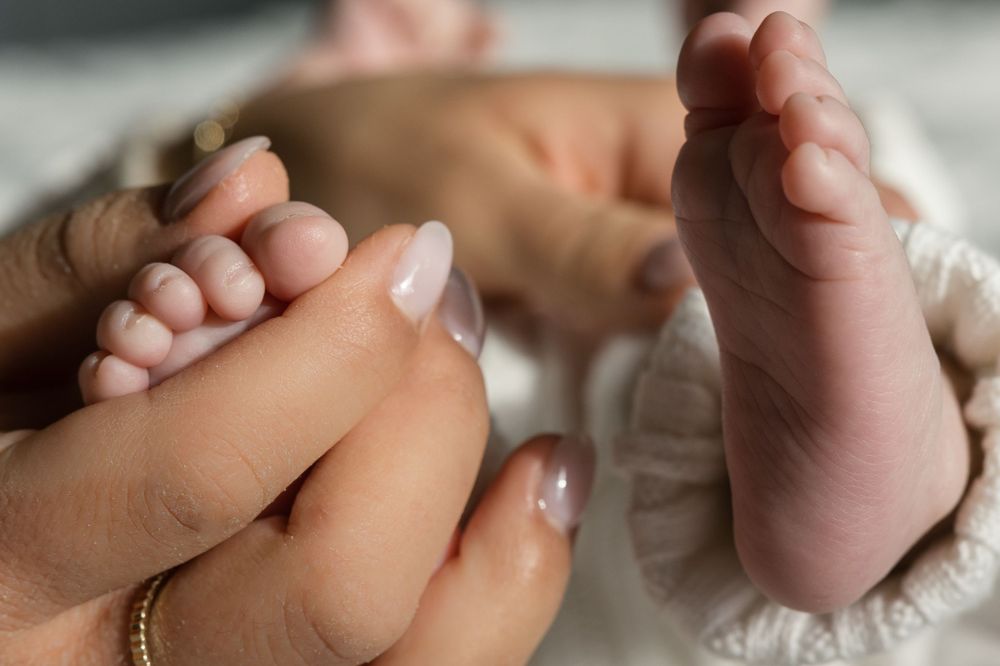 Close-up of parent's hands holding baby's tiny feet.