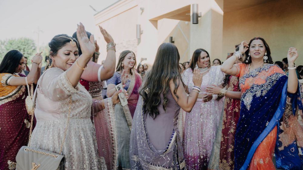 Group dancing and celebrating in colorful traditional South Asian wedding attire.