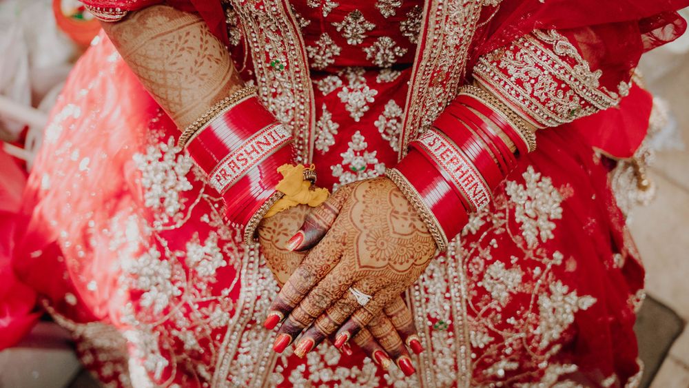 Traditional red and gold bridal attire with detailed embroidery and jewelry.