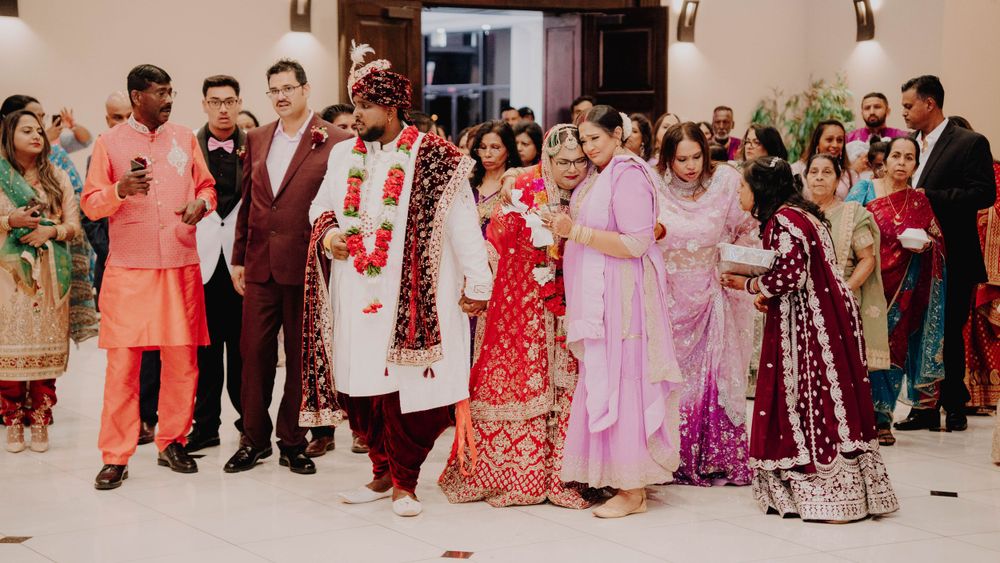 Wedding party and guests in colorful traditional attire celebrating in venue hallway.