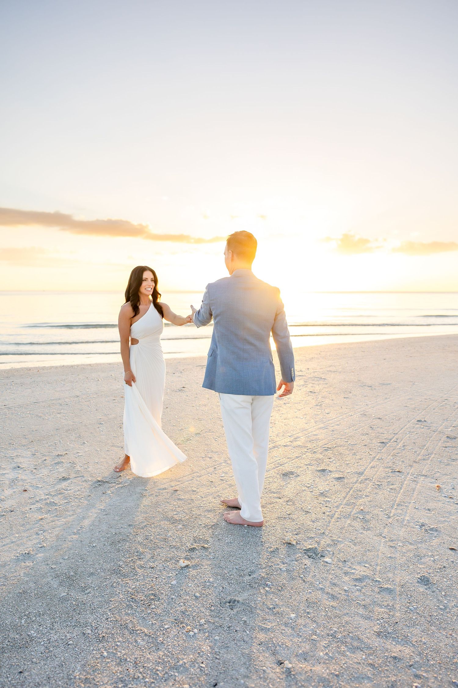 Interracial bride and groom share tender romantic kiss near marina at golden hour wedding portraits.