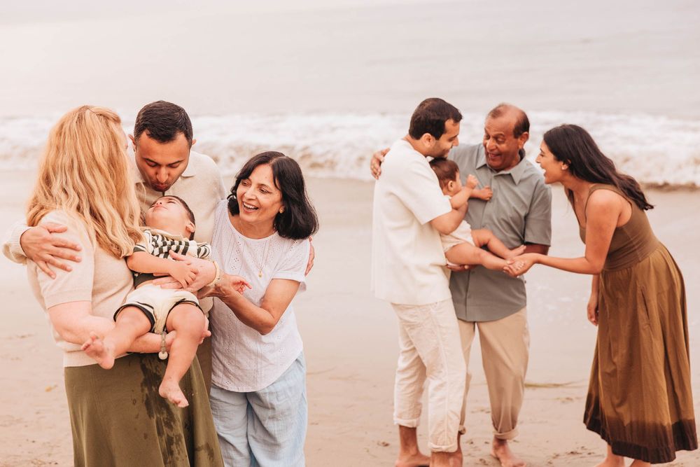Multiple families gathered on a beach at sunset sharing special moments together.
