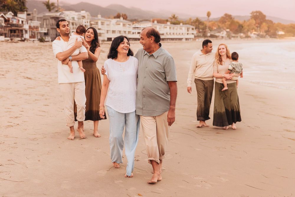 People enjoying a casual stroll along a scenic beach at sunset with palm trees in the background.