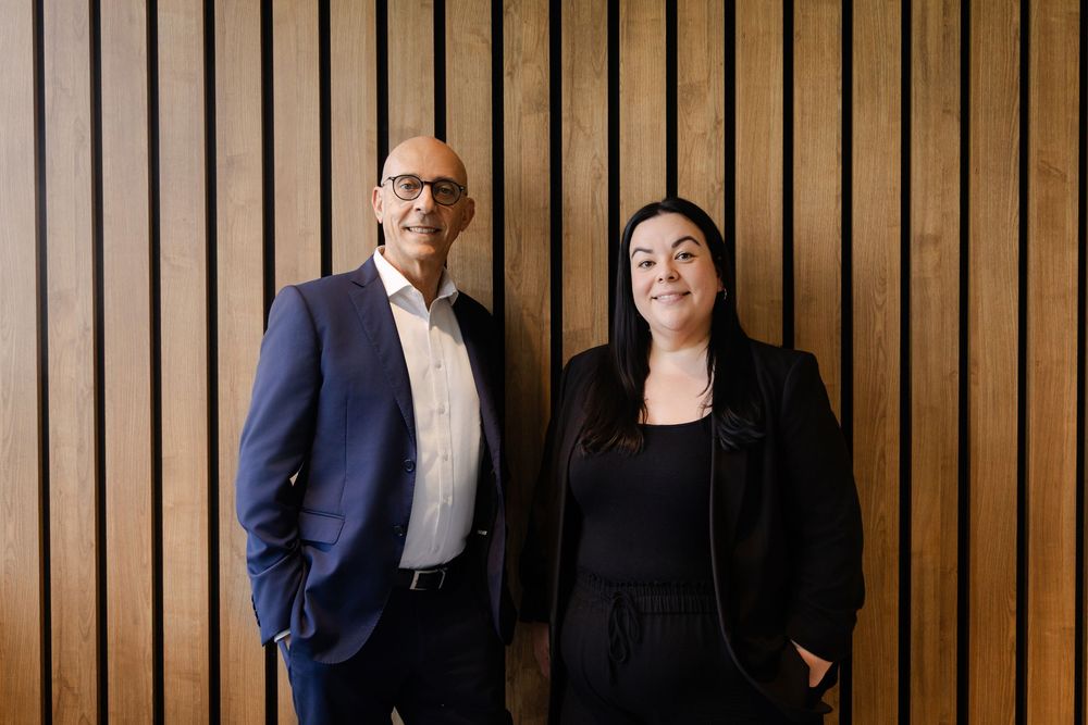 Professional business team stands together against modern wood paneled wall in office setting.
