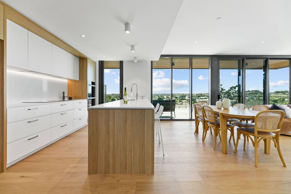 Modern open concept apartment interior with panoramic windows and minimalist wooden furniture in natural light.