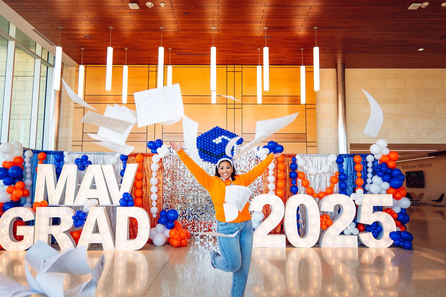 Graduation display with large white and blue letters spelling 'MAY GRAD 2023' with balloon decorations.