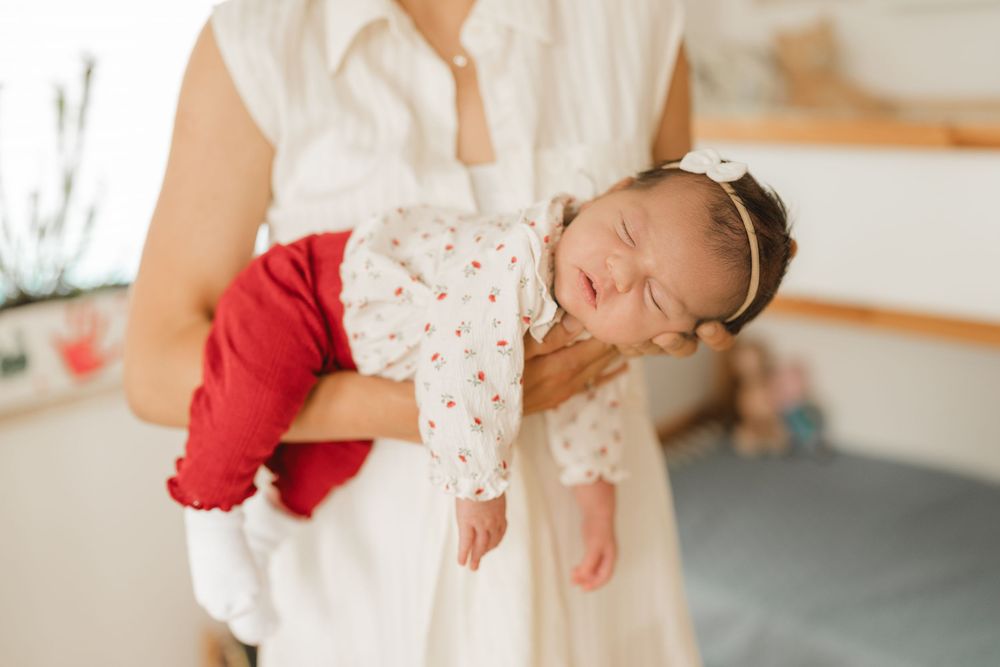 Eltern mit neugeborenen Baby auf dem Arm - Liebevolle Babyfotografie im eigenen Zuhause in Biberach von Ramona Maier