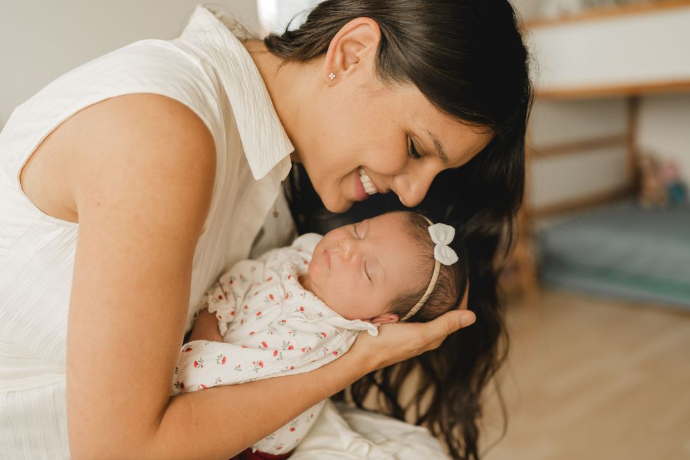 Eine Mama mit ihrem neugeborenen Baby auf dem Arm - Liebevolle Babyfotografie im eigenen Zuhause in Biberach von Ramona Maier