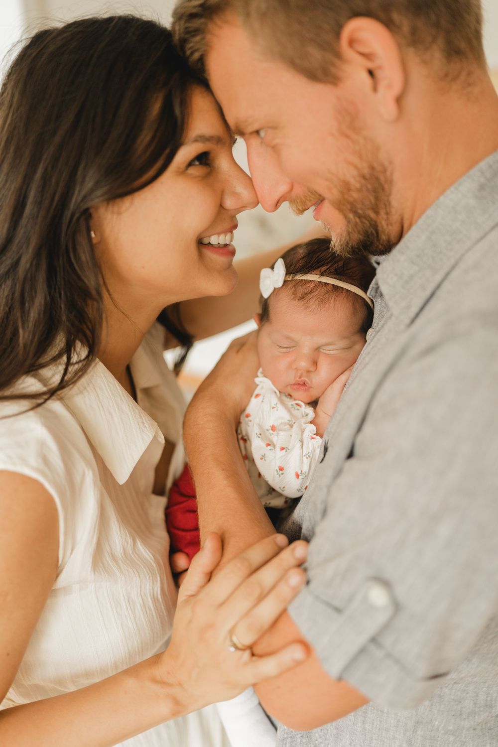 Eltern mit neugeborenen Baby auf dem Arm - Liebevolle Babyfotografie im eigenen Zuhause in Biberach von Ramona Maier