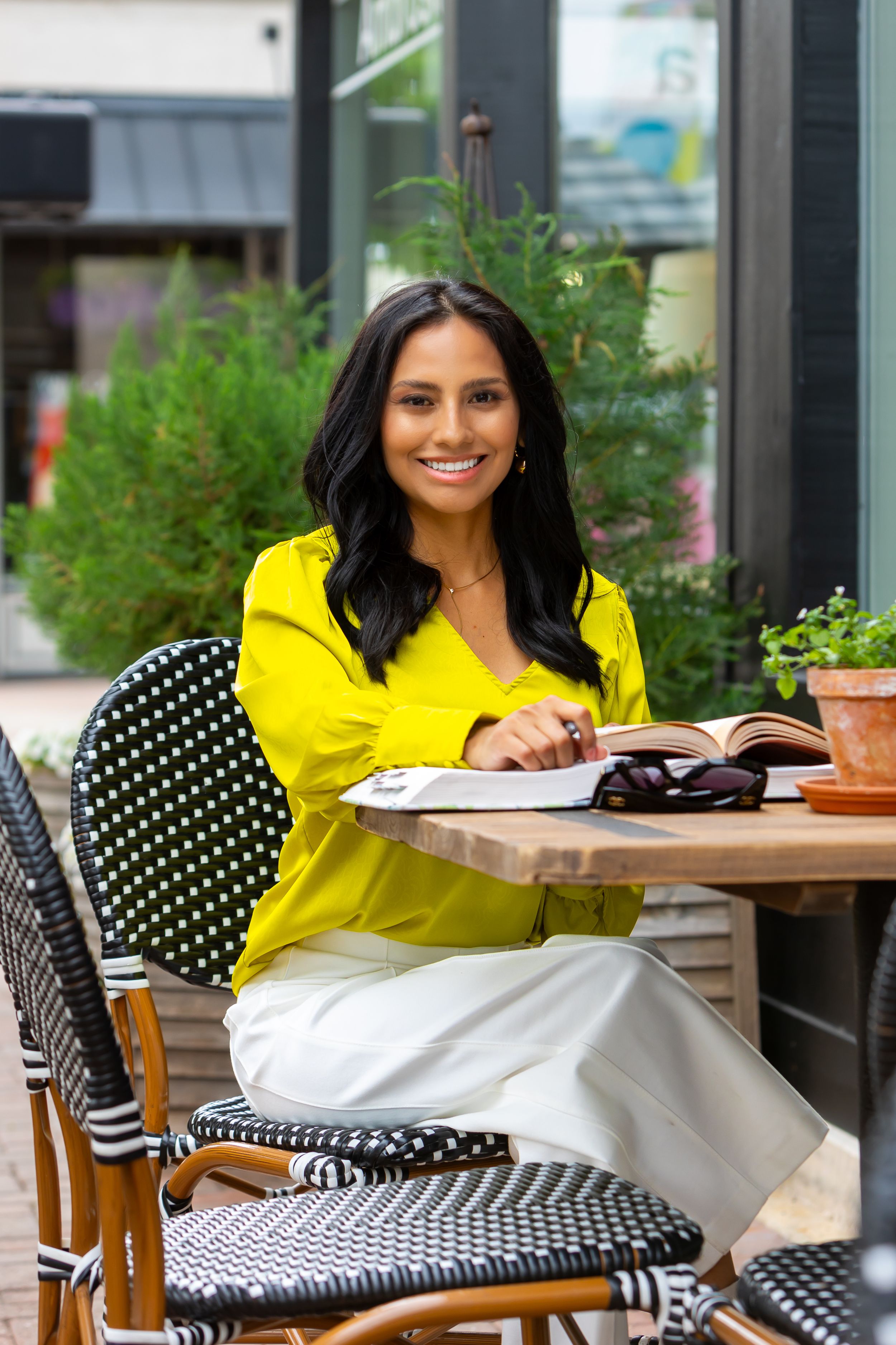 Outdoor cafe scene with polka dot chair and yellow blouse against greenery.