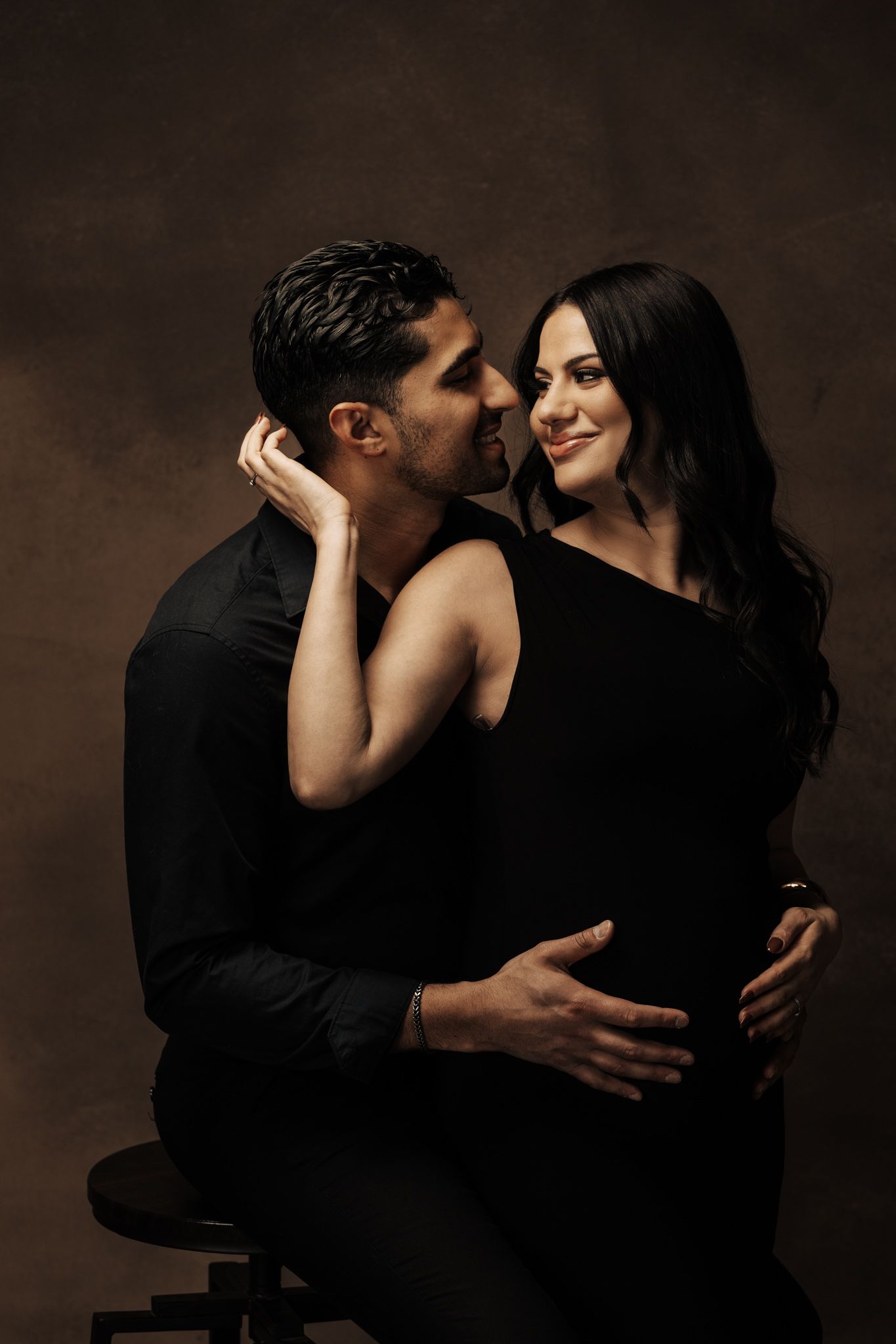 Intimate couple photography series showing romantic poses against dark background in black attire.
