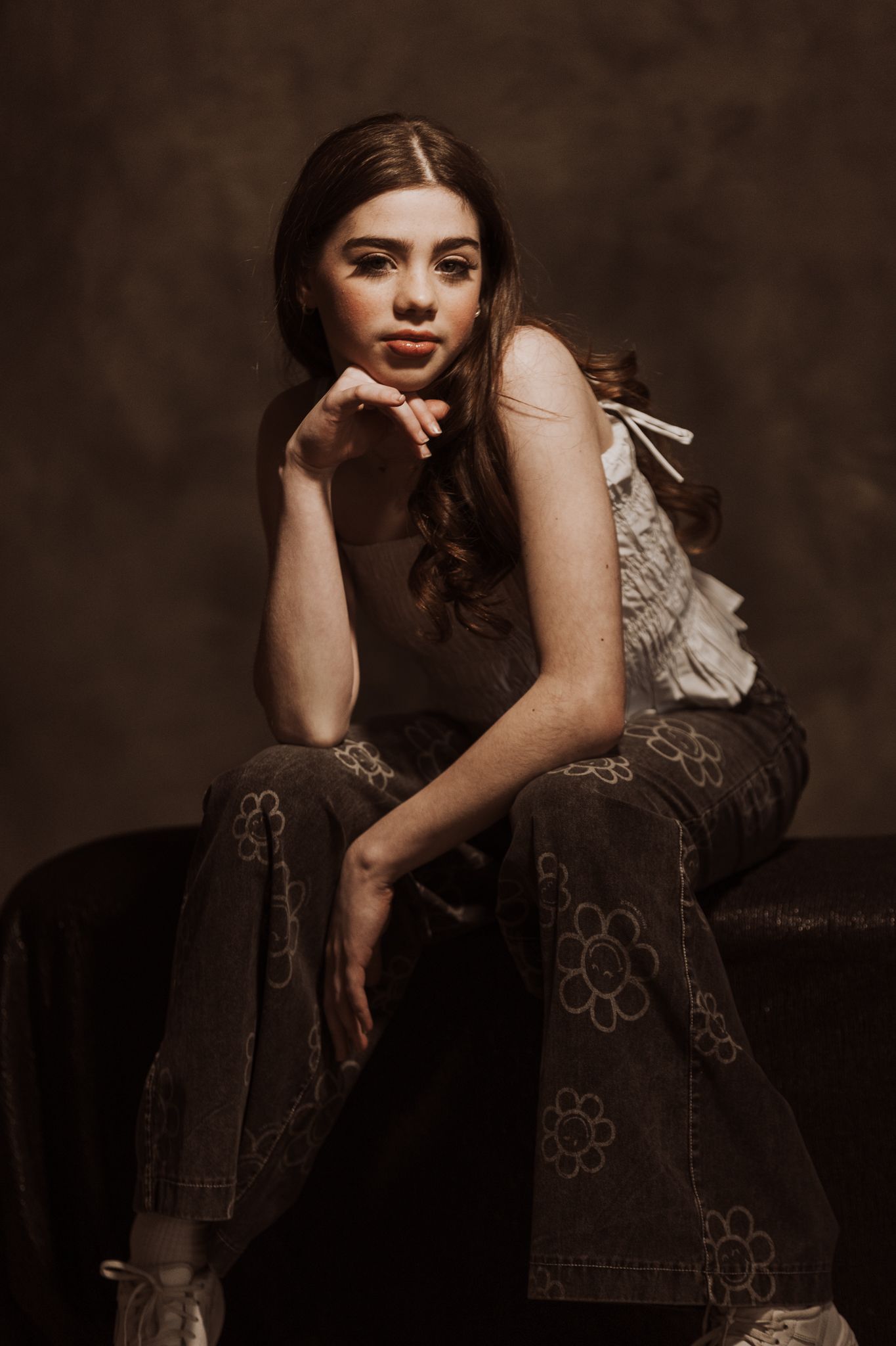 Moody fashion portraits in embellished dark dress against brown backdrop.