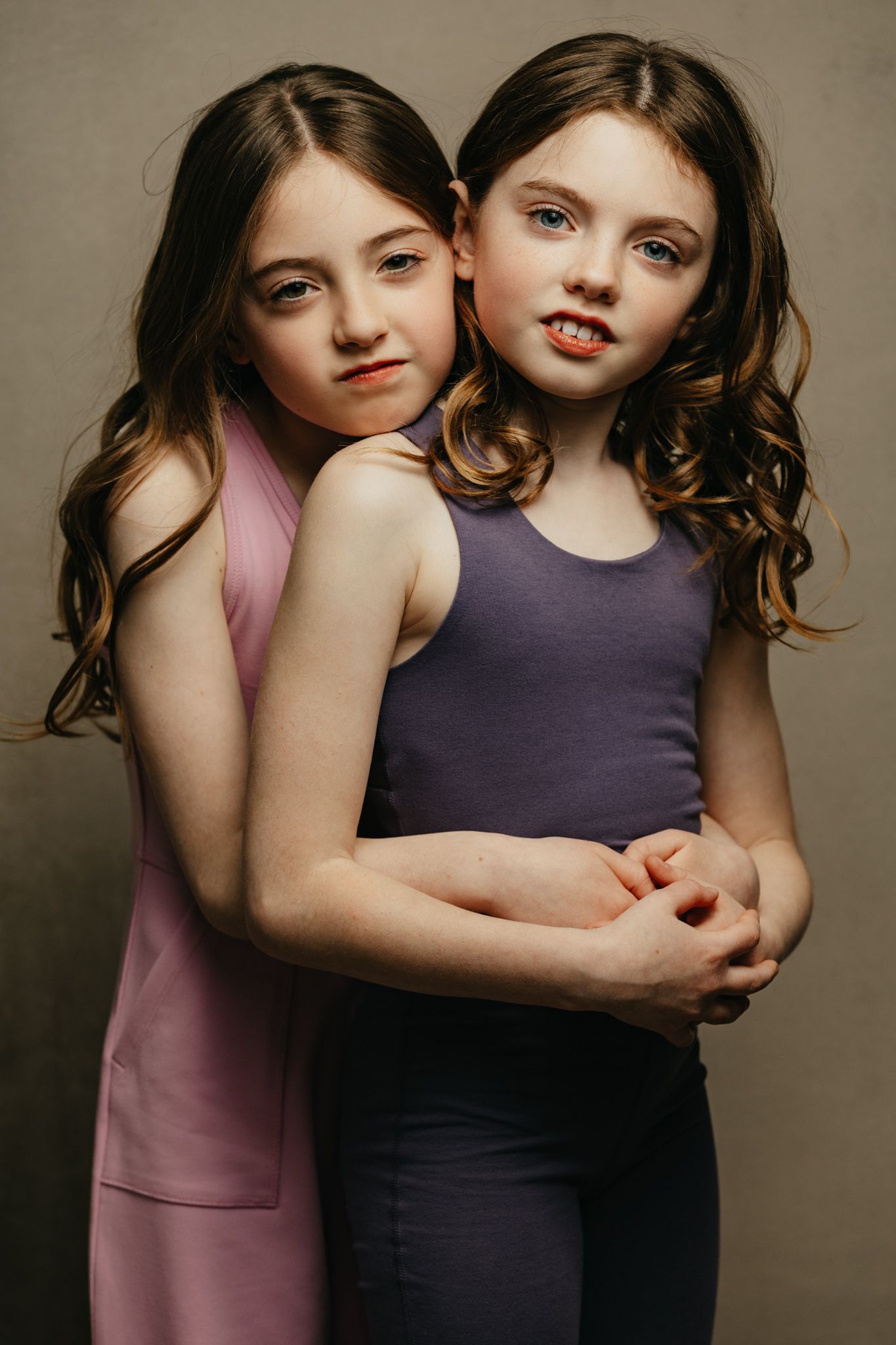 Two young people in tank tops pose together in a studio portrait against a neutral background.