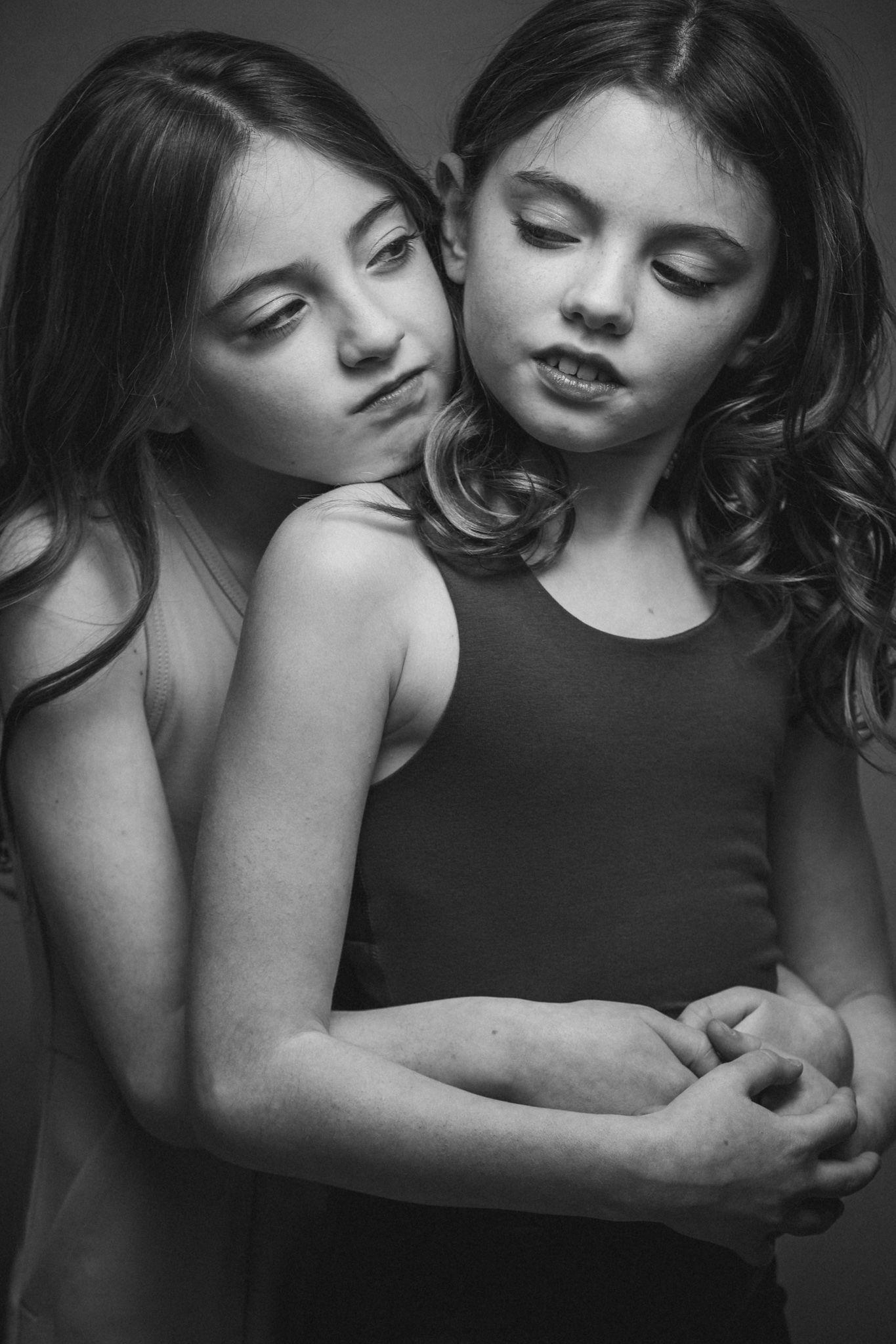 Black and white artistic portrait of two people in an intimate pose with closed eyes and tender embrace.