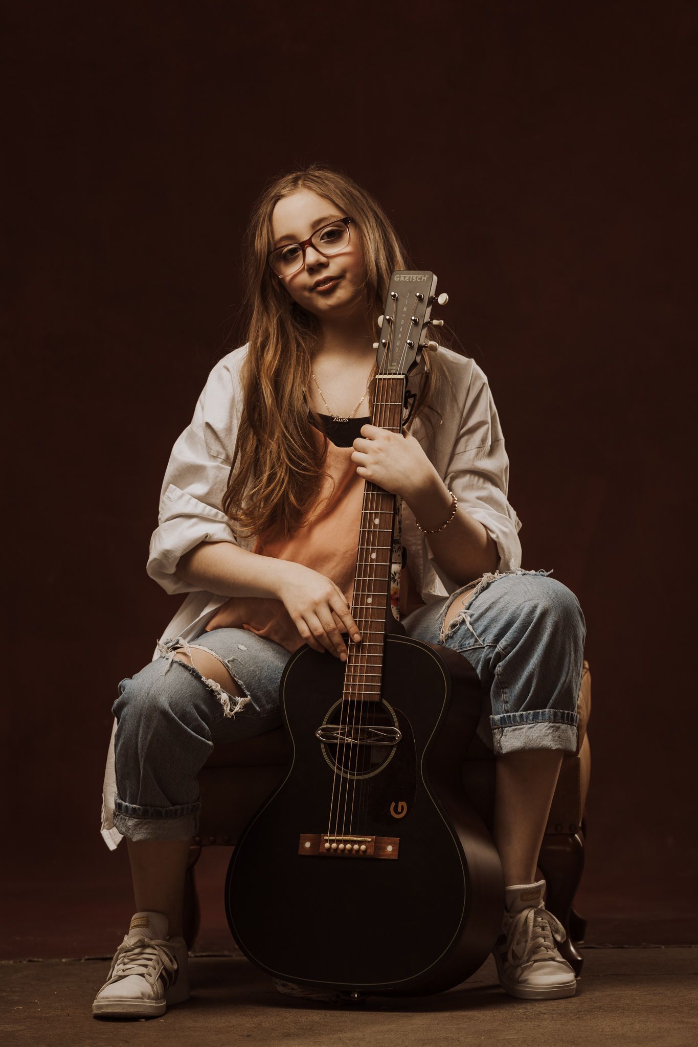 A series of five moody portraits showing someone sitting with an acoustic guitar against a dark brown background.