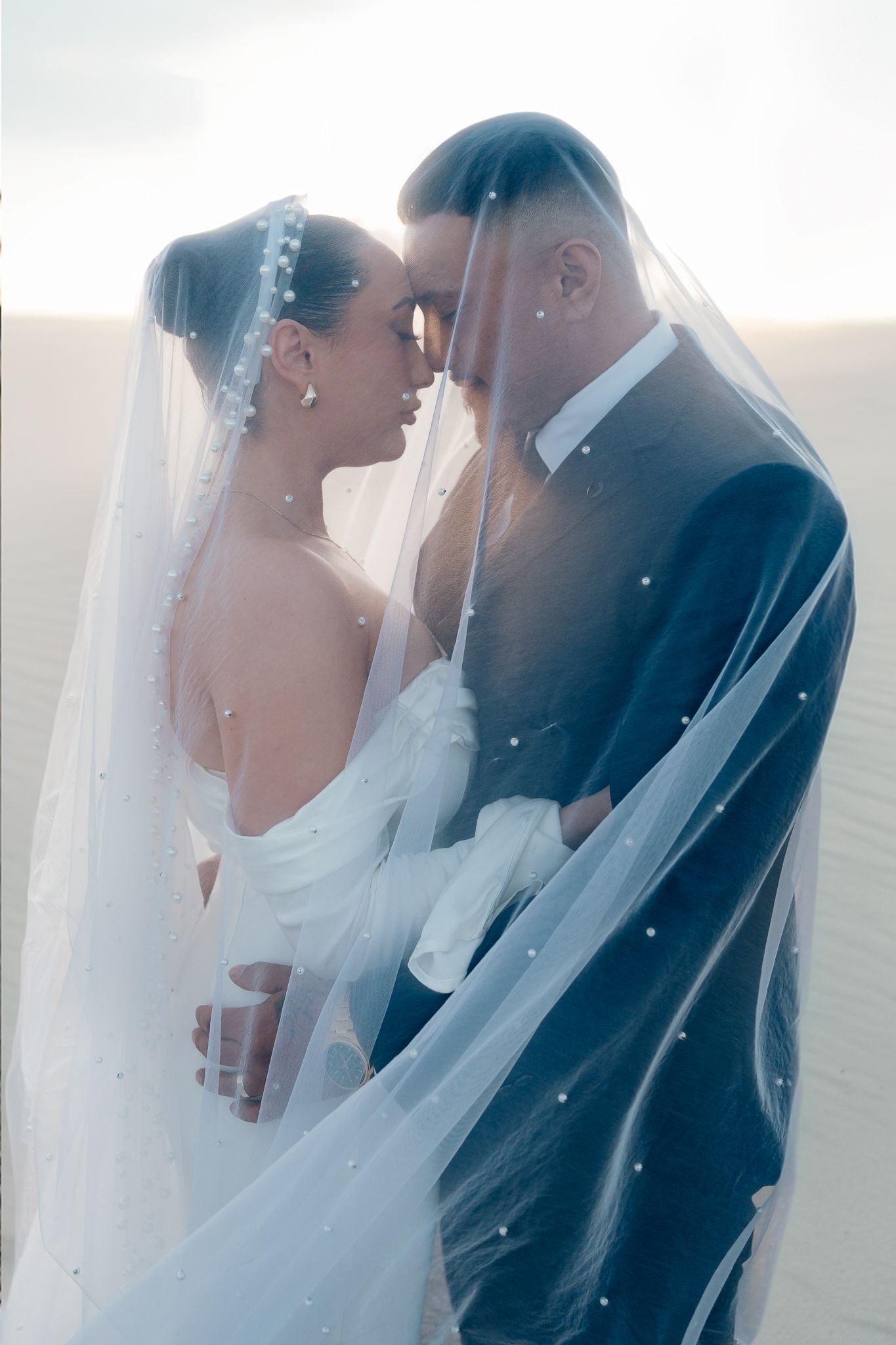 Romantic wedding portraits with flowing veil captured in dreamy light.