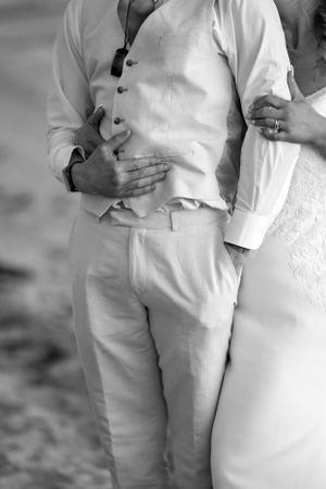 Close up of groom's classic white linen suit and vest on a beach.