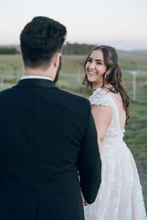 Candid moment between newlyweds on grassy hillside during golden hour.
