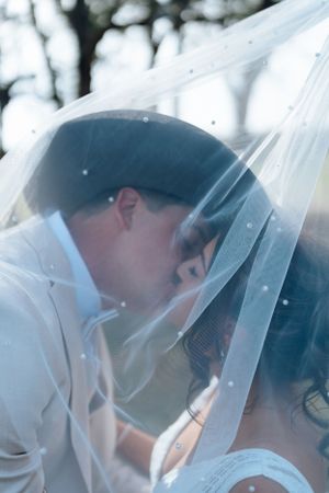 Romantic moment captured through a delicate white veil in soft lighting.