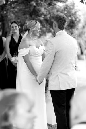 Wedding ceremony moment with couple holding hands at outdoor venue.