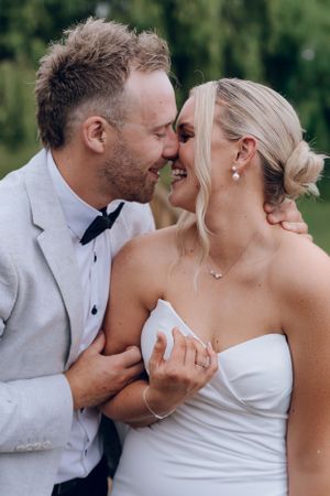 Candid moment of laughter between newlyweds in outdoor setting.