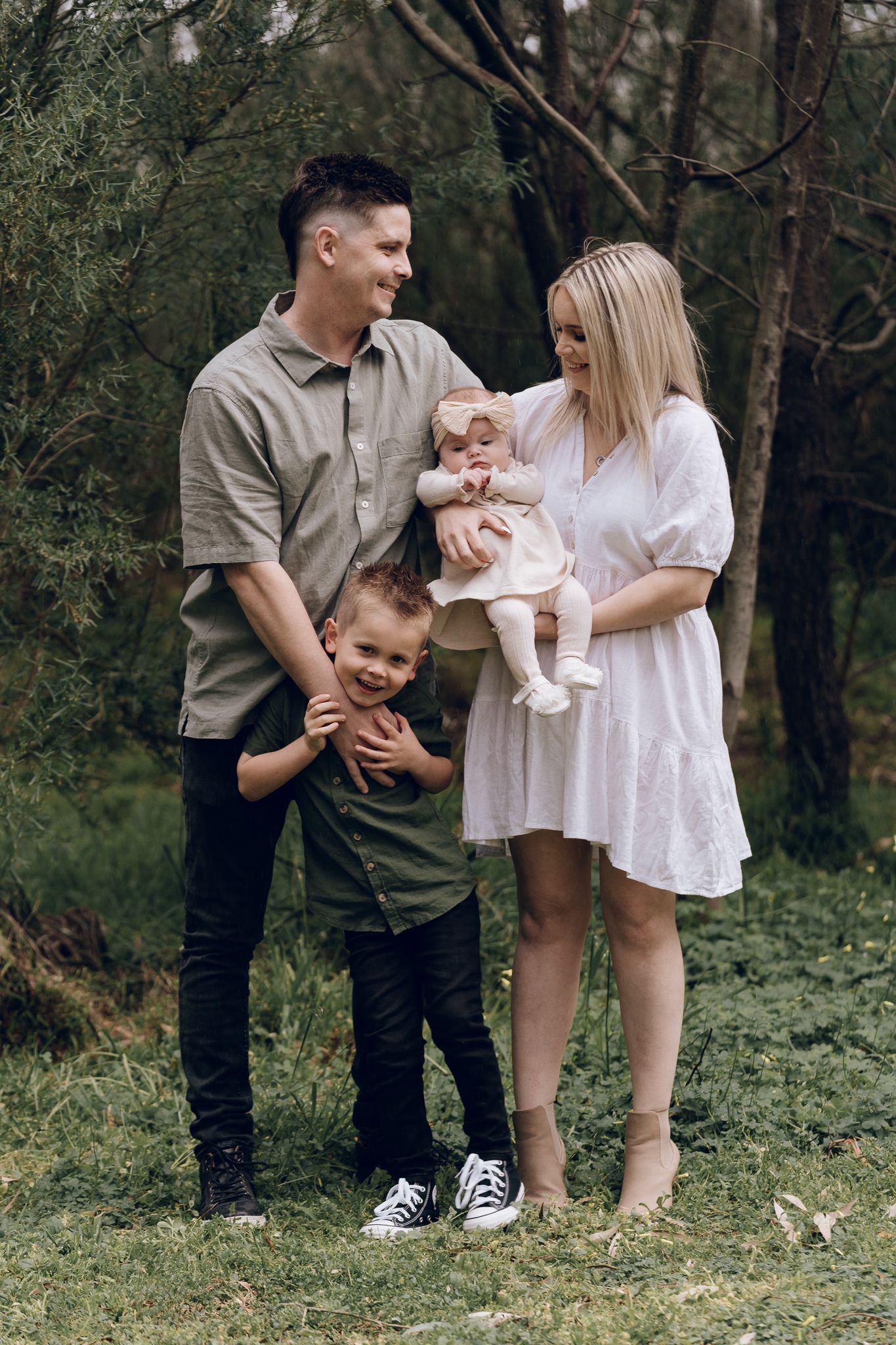 Young family playing together outdoors in casual clothing on grassy field.