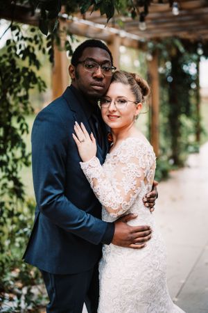 Romantic wedding portrait of couple embracing in an elegant lace gown and navy suit.