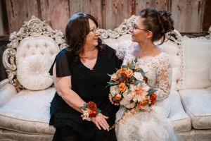 Two people share an intimate moment on an ornate vintage couch with autumn-colored floral bouquet.