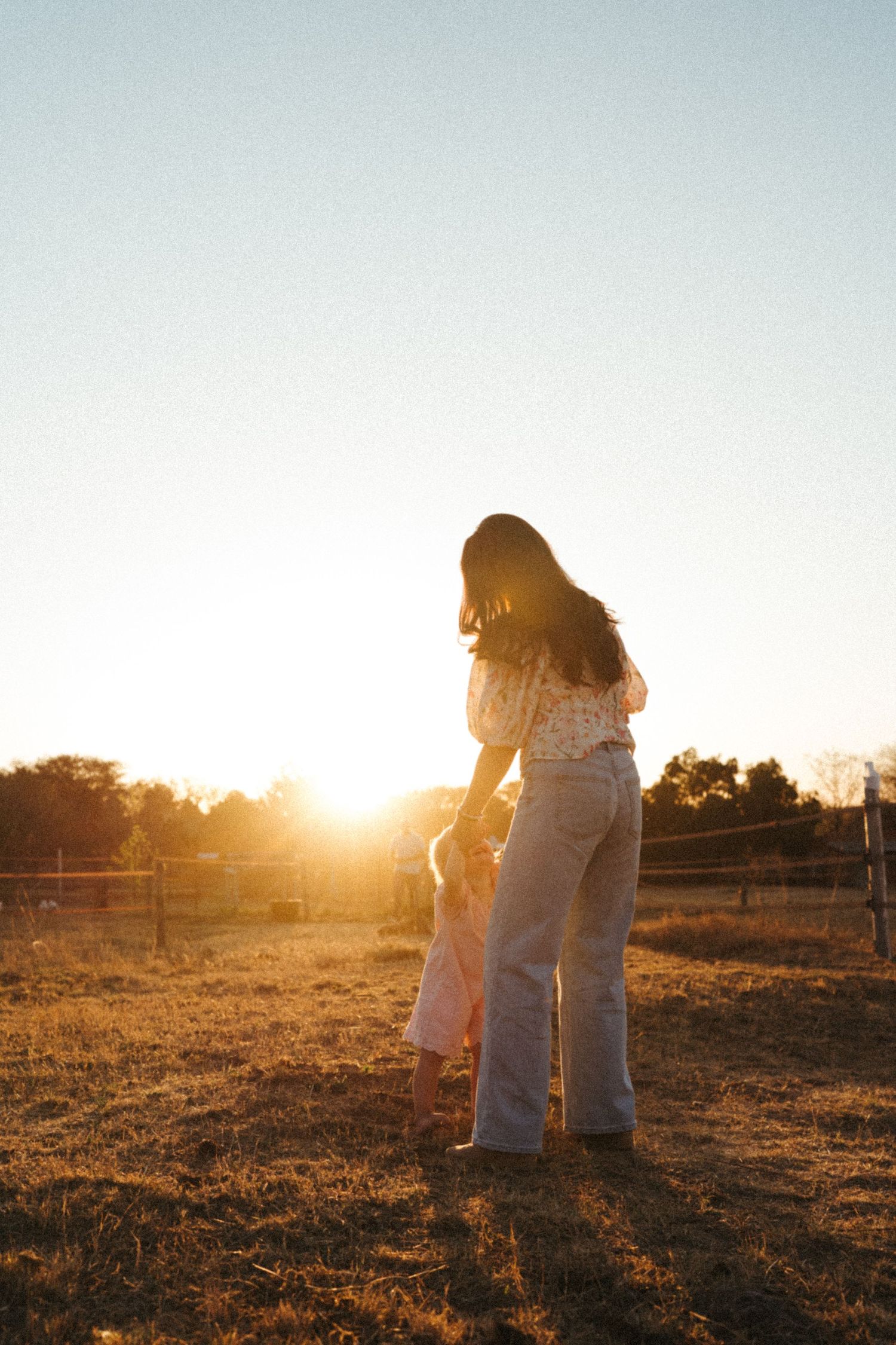 A silhouette of two people embracing during sunset in a rustic field.