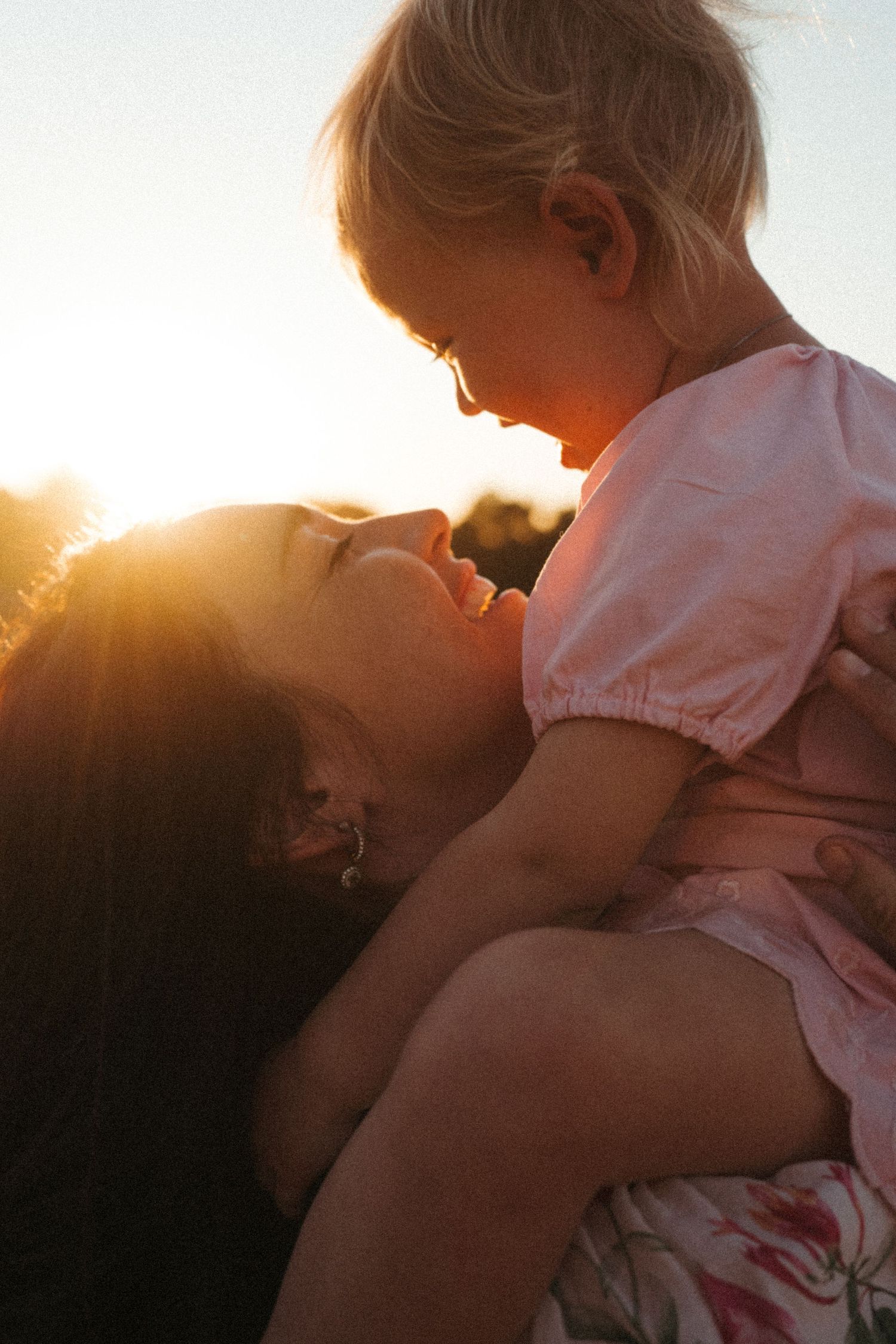 Silhouettes embrace against a bright sunset sky in a touching outdoor scene.