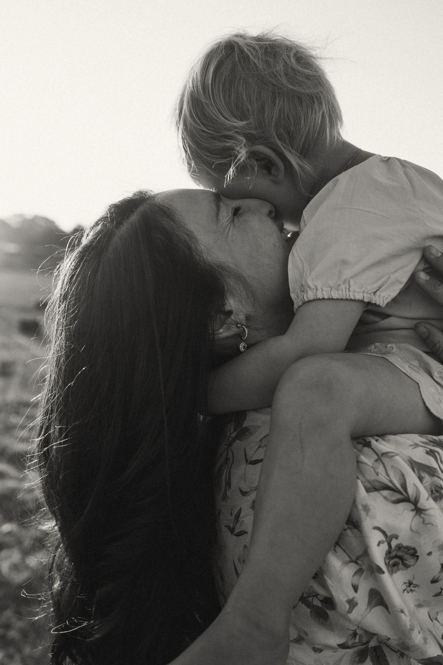 An intimate black and white portrait showing a gentle embrace outdoors.
