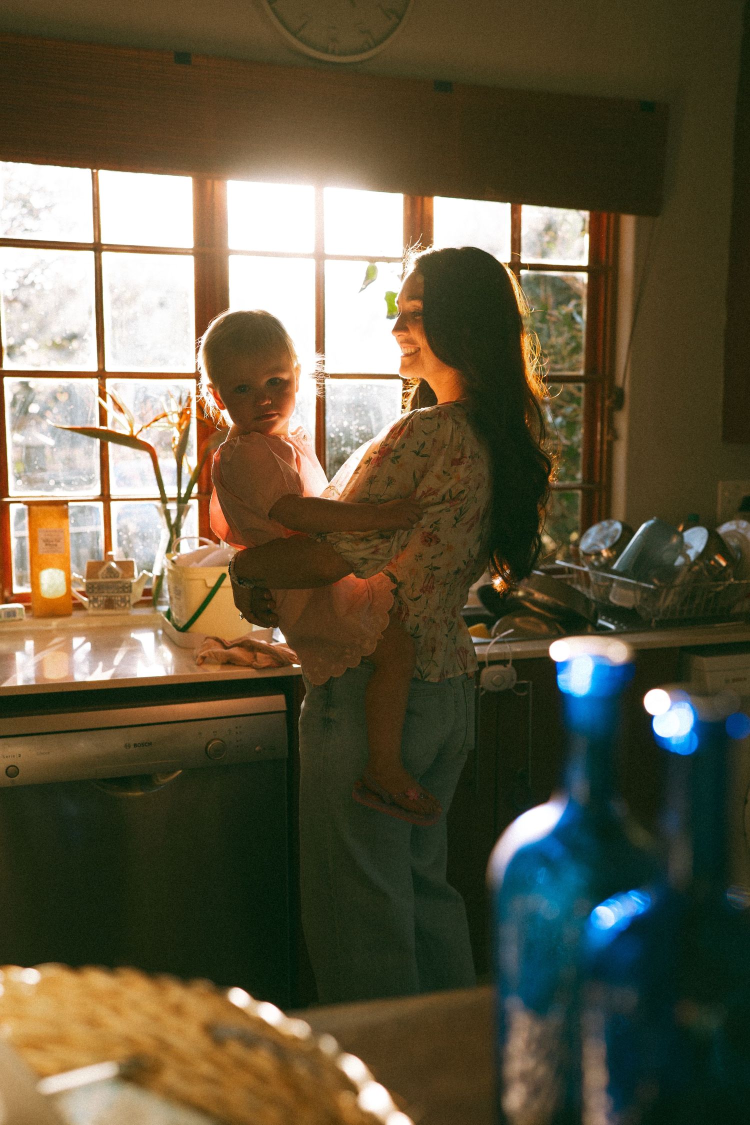 Sunlight streams through windows into a cozy kitchen scene with warm ambient lighting.