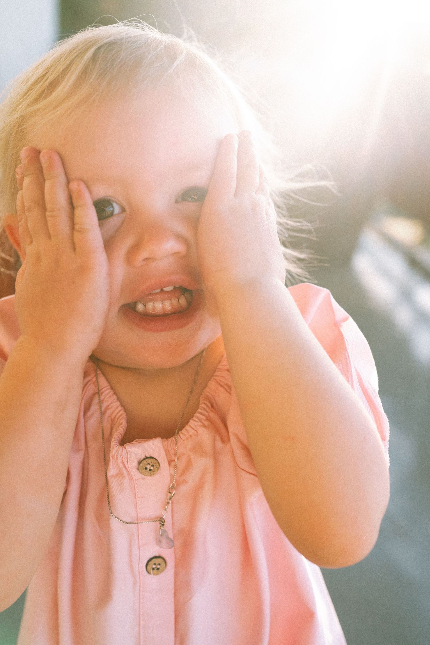 A playful peek-a-boo moment captured in soft, bright sunlight.