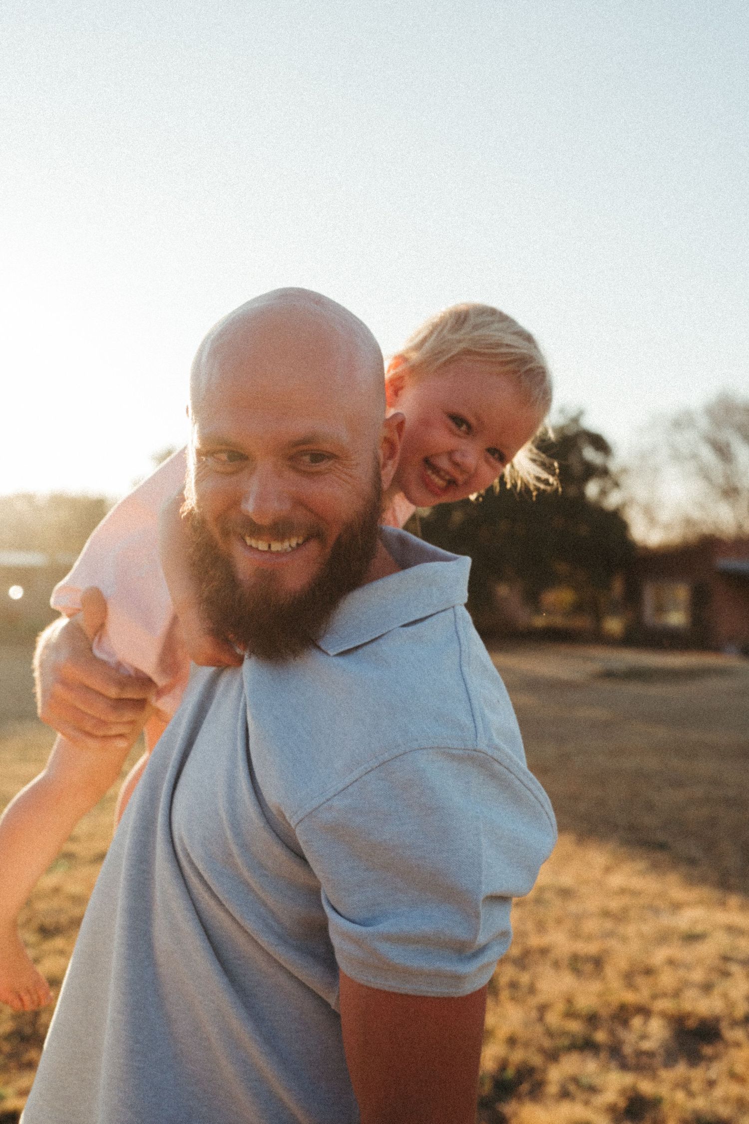 Joyful outdoor portrait session with warm sunset lighting in a rural field setting.