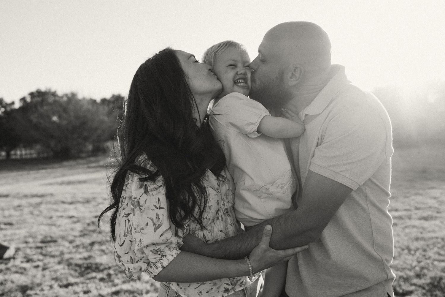 Intimate family moments captured during sunset in a grassy field.
