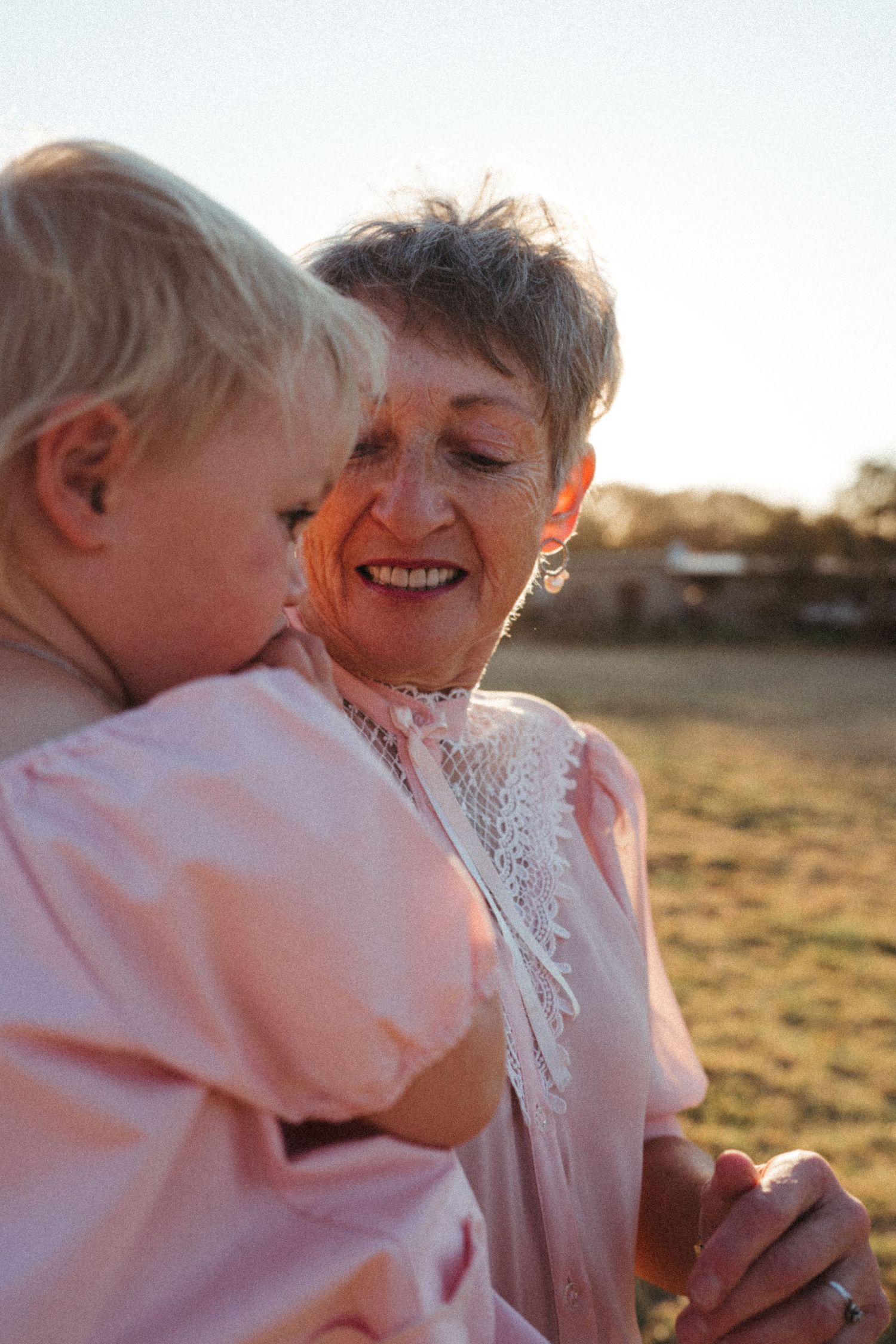 Sweet interaction between parent and child in pink clothing during golden hour.