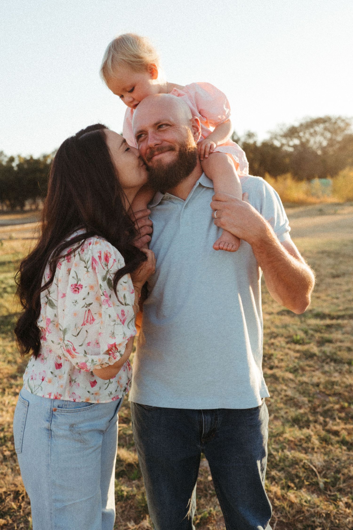 A family shares tender moments together in a sun-drenched field during golden hour.