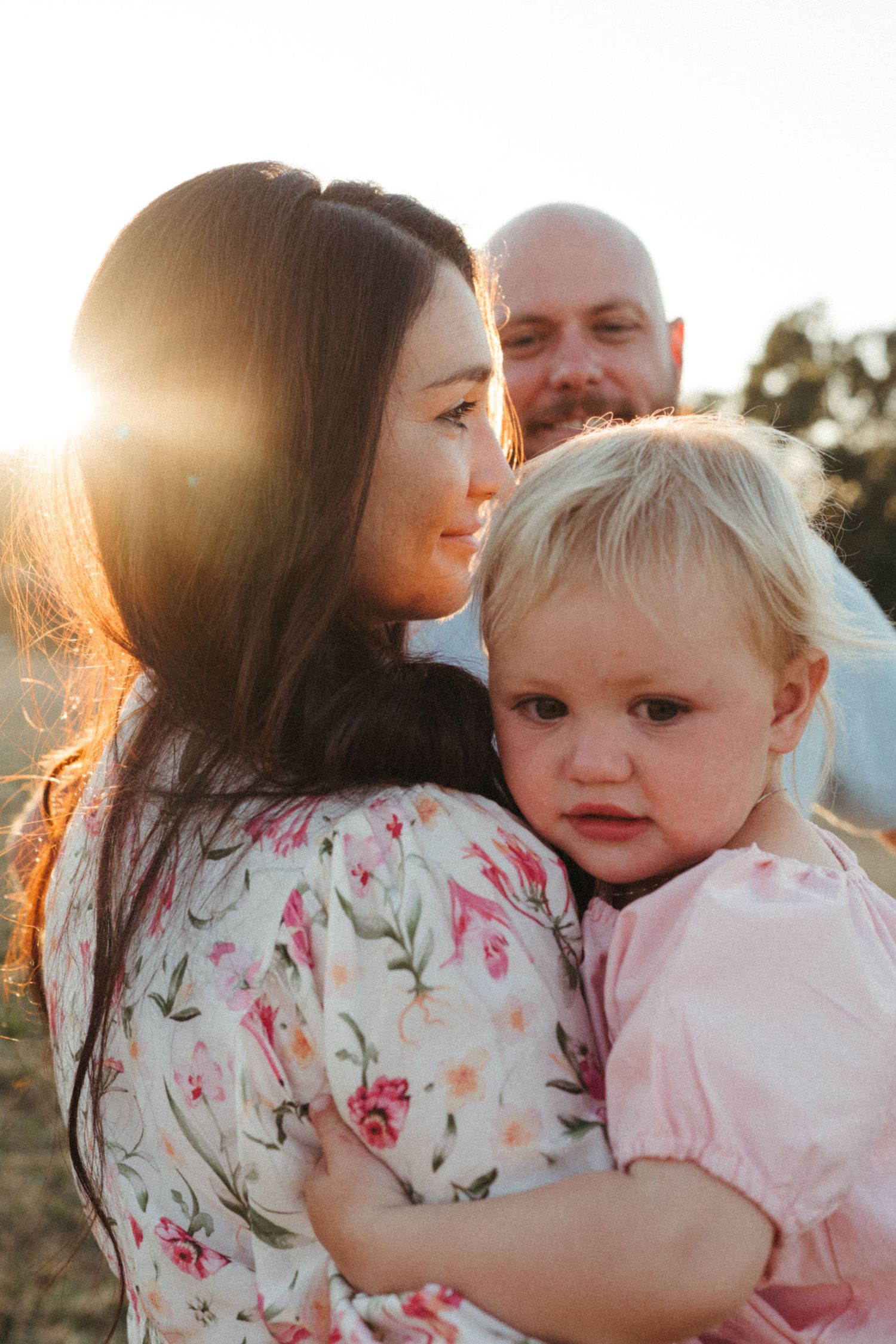 Family portrait session in floral dress and casual wear during golden hour.