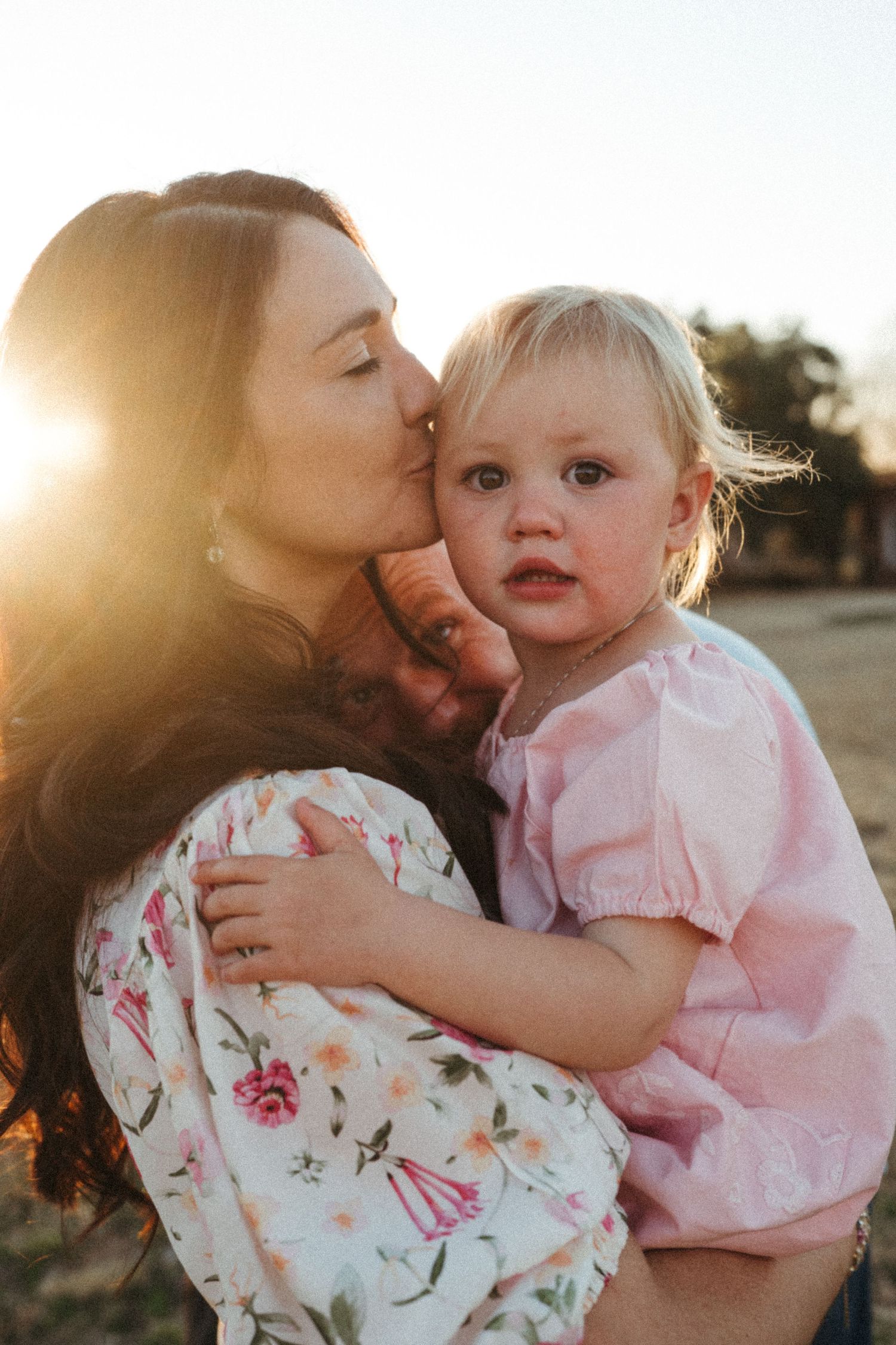 Sweet candid moments between family members during an outdoor photo session at sunset.