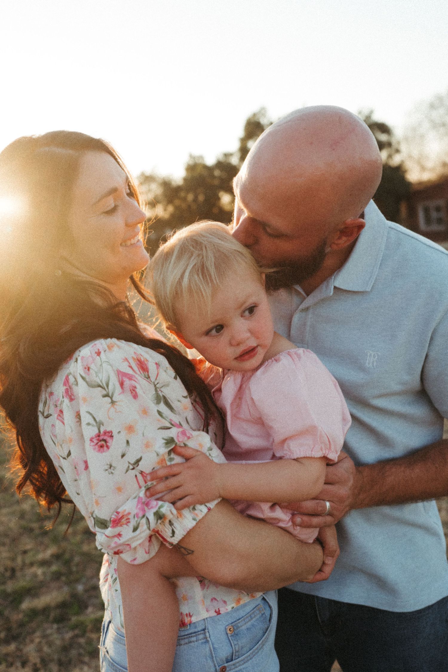 Loving family embraces during golden hour photoshoot in an outdoor setting.