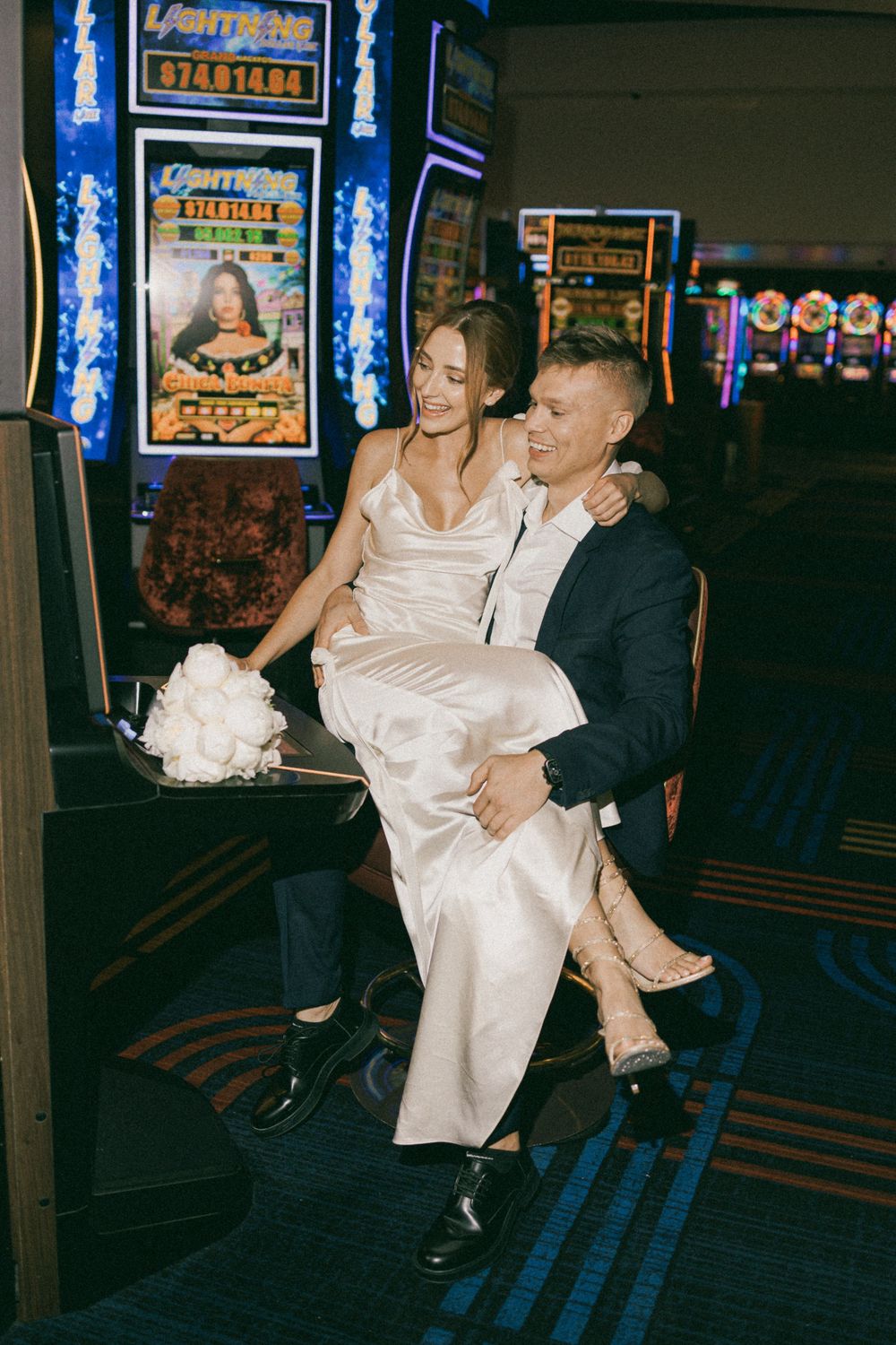 People dancing and having fun in a dimly lit casino arcade or entertainment venue with neon blue lighting.