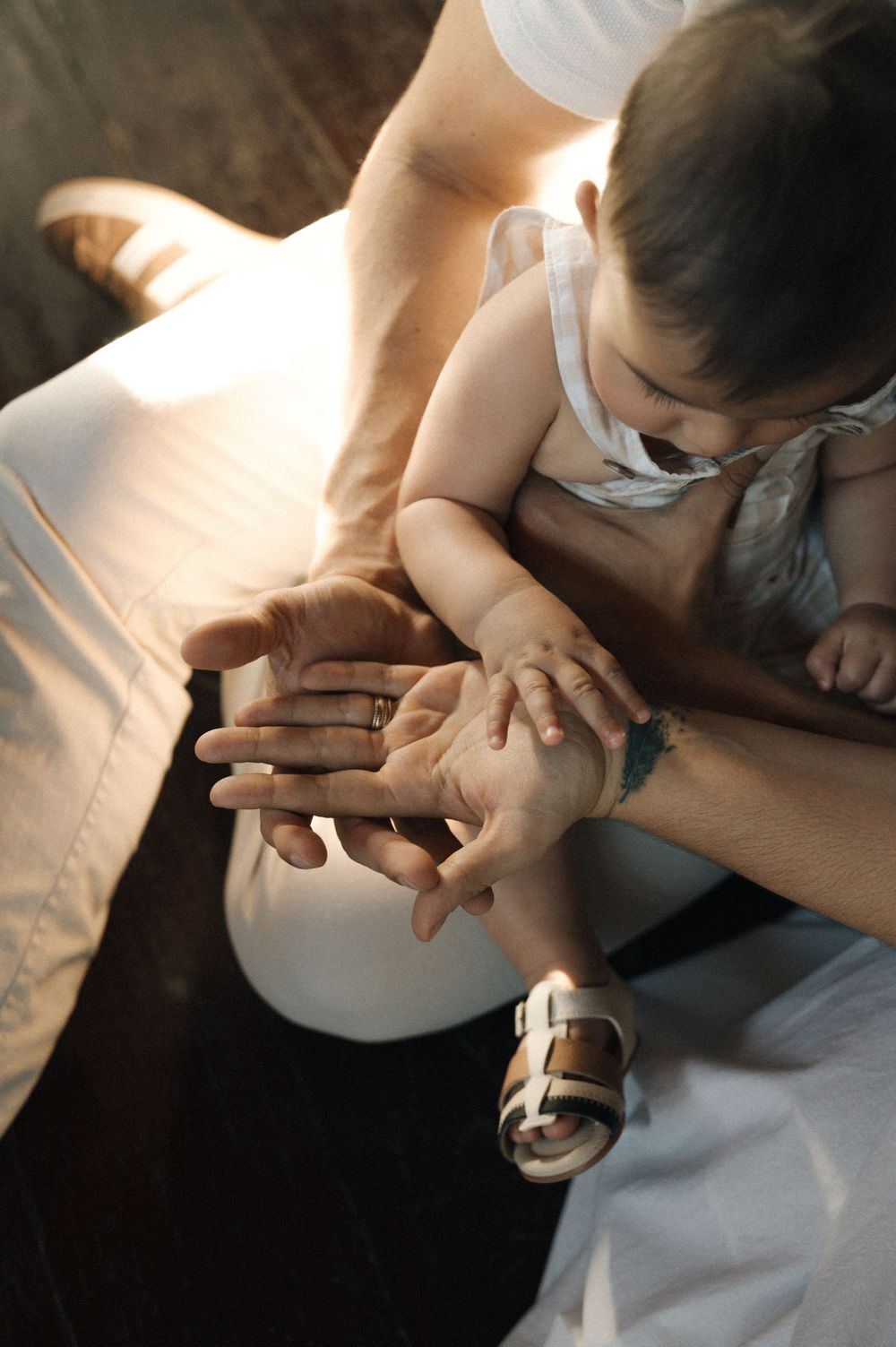 Small child's hands gently touching an adult's palm in soft natural lighting.